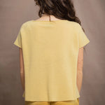a woman wears a pure 100% cashmere tee sweater in butter yellow over silk trousers in butter yellow