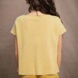 a woman wears a pure 100% cashmere tee sweater in butter yellow over silk trousers in butter yellow
