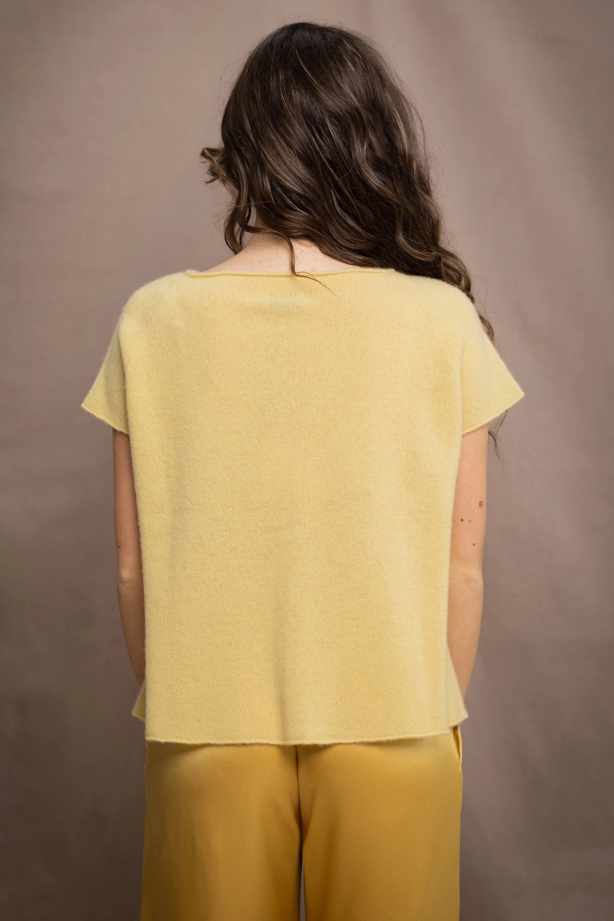 a woman wears a pure 100% cashmere tee sweater in butter yellow over silk trousers in butter yellow