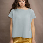 Woman wearing a light pale blue turquoise cashmere tee sweater over yellow silk trousers