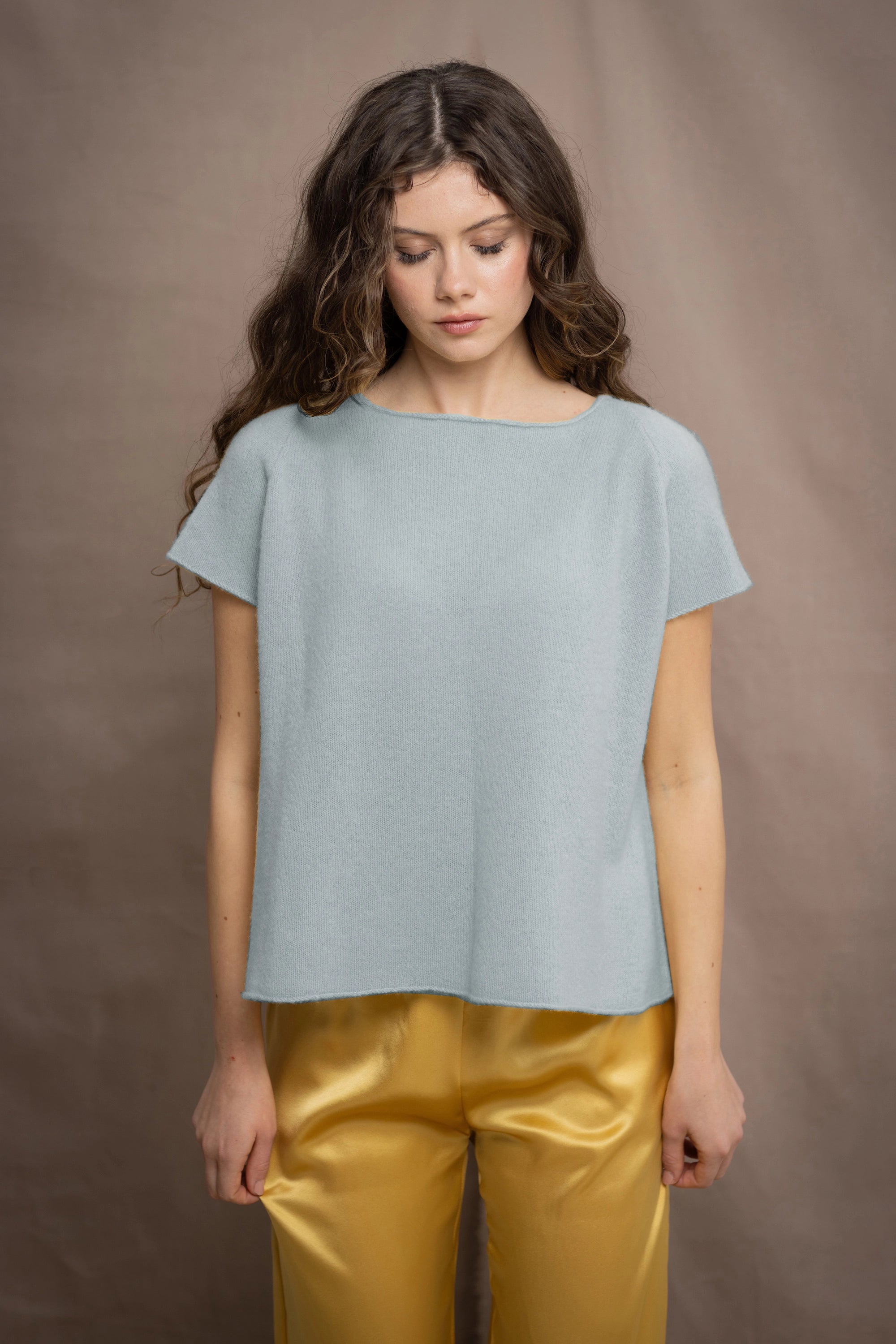 Woman wearing a light pale blue turquoise cashmere tee sweater over yellow silk trousers