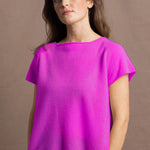 a woman wears a neon pink cashmere tee sweater over black silk shorts