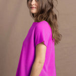 a woman wears a neon pink cashmere tee sweater over black silk shorts