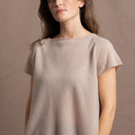 A woman wears a 100% cashmere tshirt in beige with pure silk shorts in black