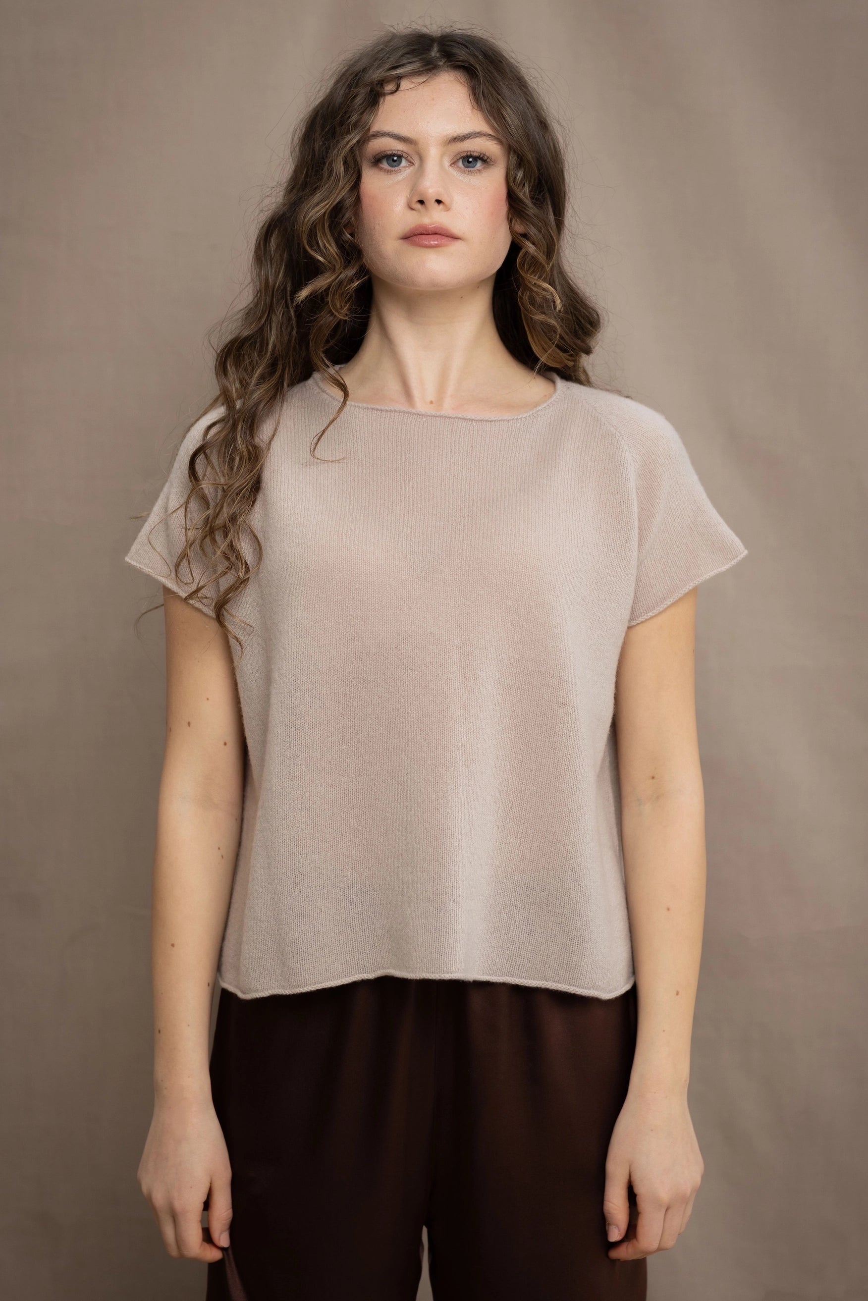 a woman wears a beige cashmere tee with silk trousers in chocolate brown