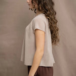 a woman wears a beige cashmere tee with silk trousers in chocolate brown