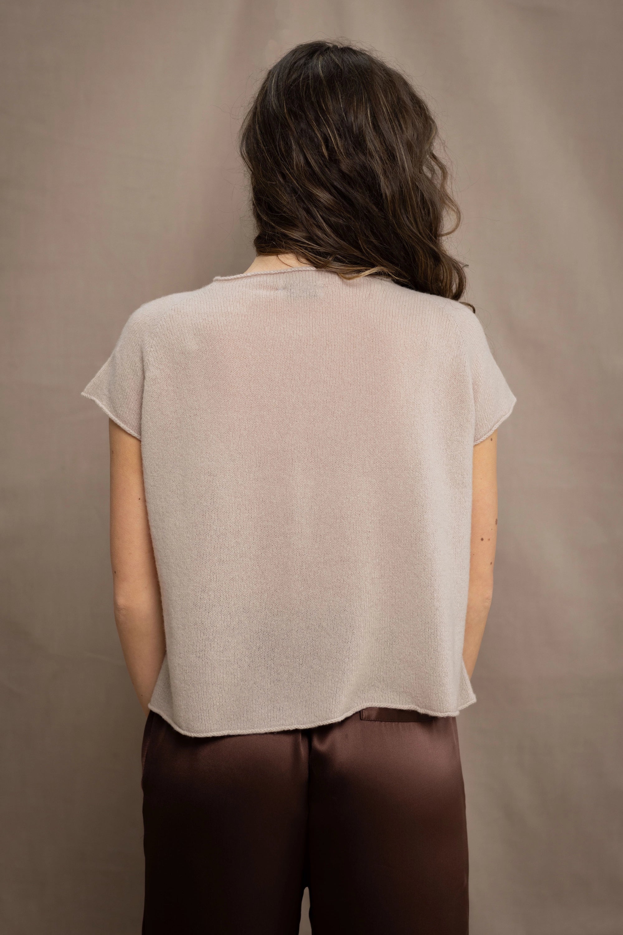 a woman wears a beige cashmere tee with silk trousers in chocolate brown