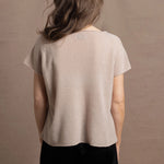 A woman wears a 100% cashmere tshirt in beige with pure silk shorts in black