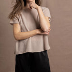A woman wears a 100% cashmere tshirt in beige with pure silk shorts in black