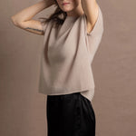 A woman wears a 100% cashmere tshirt in beige with pure silk shorts in black