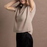 A woman wears a 100% cashmere tshirt in beige with pure silk shorts in black