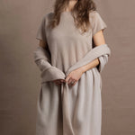 A woman wears a large cashmere shawl in beige over a matching cashmere tee