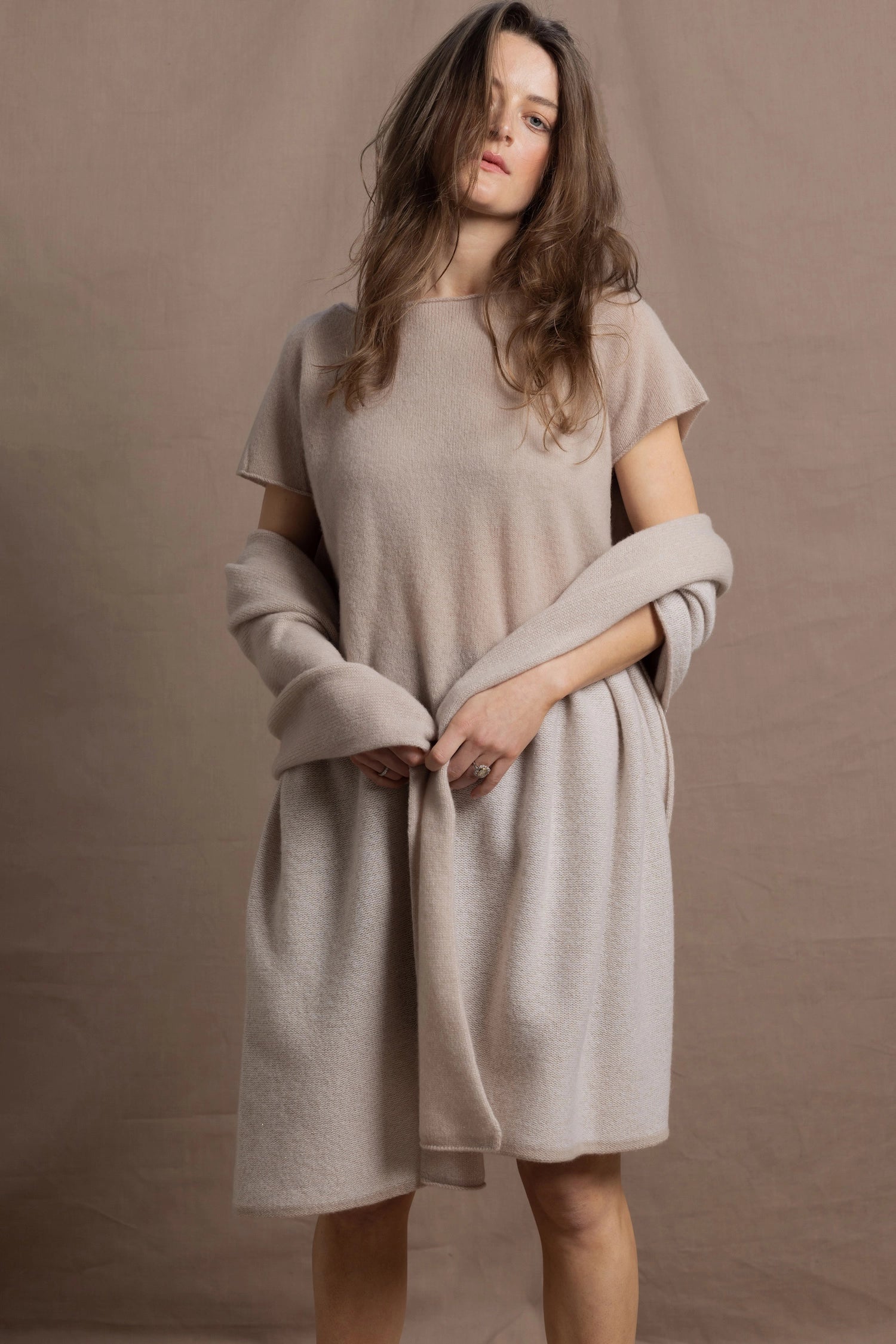A woman wears a large cashmere shawl in beige over a matching cashmere tee