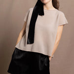 A woman wears a 100% cashmere tshirt in beige with pure silk shorts in black with a black silk tie in her hair