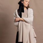 A woman wears a large cashmere shawl in beige over a matching cashmere tee