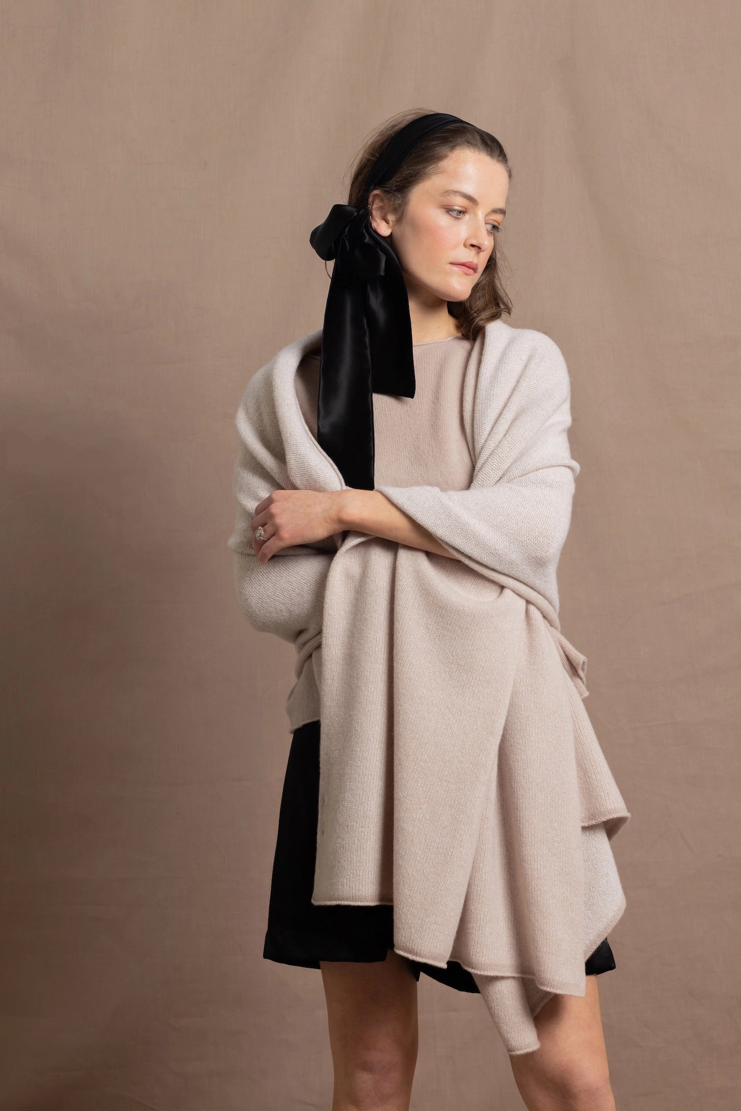 A woman wears a large cashmere shawl in beige over a matching cashmere tee