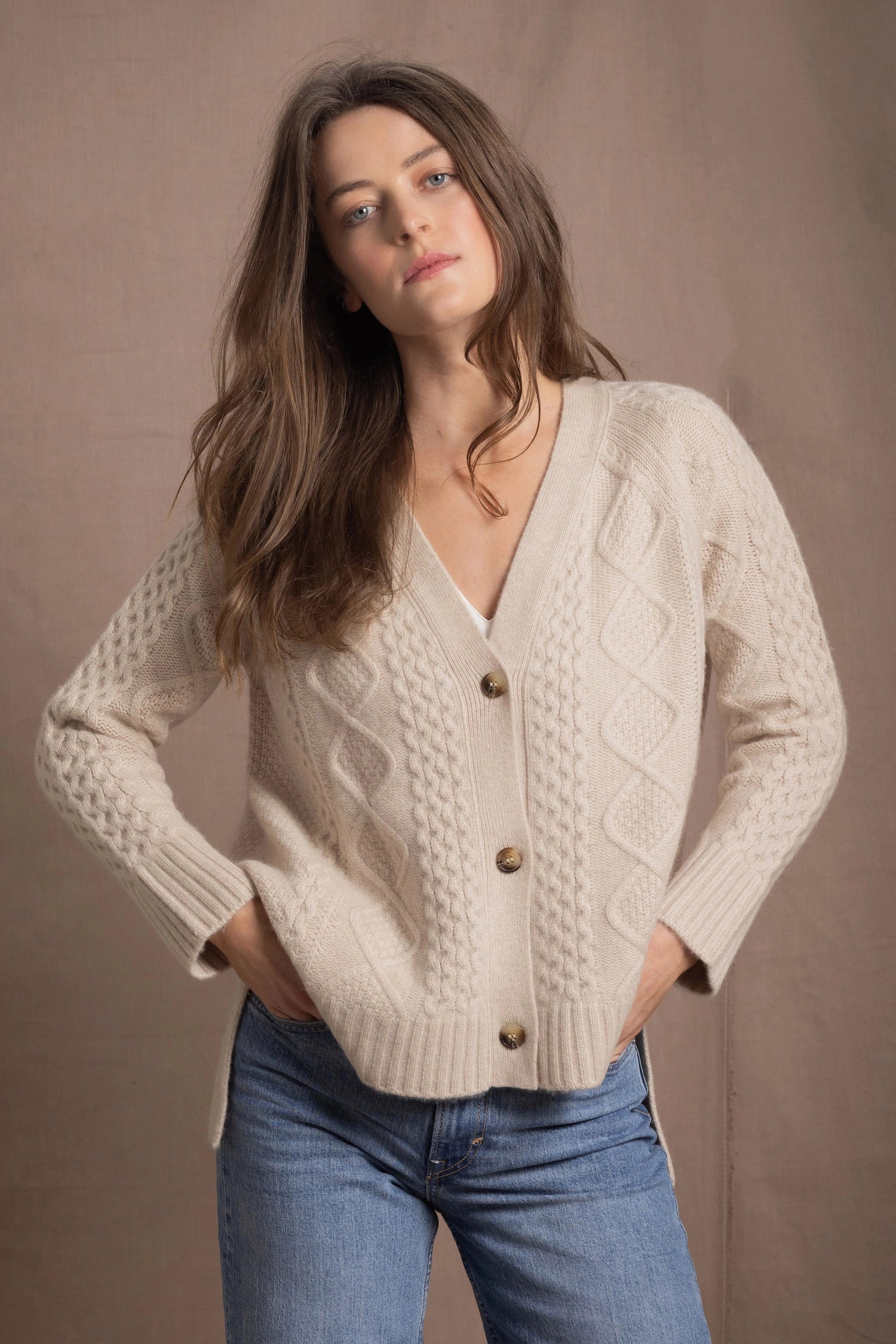 a woman wears a beige coloured cashmere aran cardigan sweater with horn buttons on it and diamond stitches