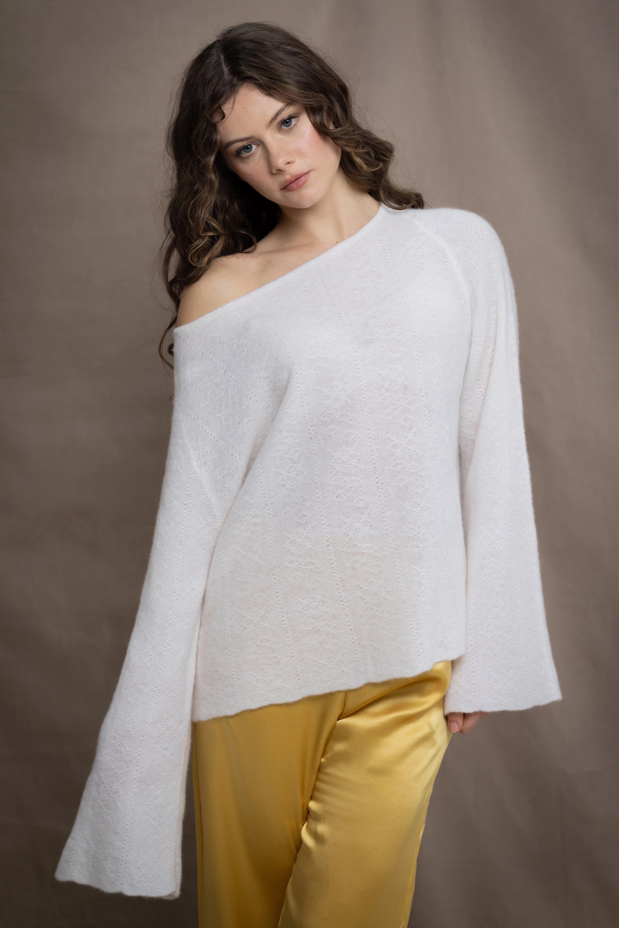 a woman wears a pure 100% cashmere sweater jumper off the shoulder in white over yellow silk trousers