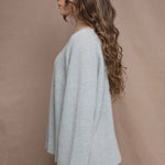 A woman wears a lightweight pointelle cashmere sweater jumper in pale blue turquoise with bronze silk skirt