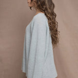 A woman wears a lightweight pointelle cashmere sweater jumper in pale blue turquoise with bronze silk skirt
