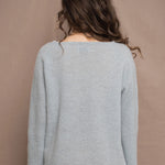 A woman wears a lightweight pointelle cashmere sweater jumper in pale blue turquoise with bronze silk skirt