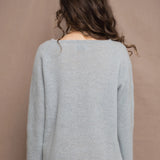 A woman wears a lightweight pointelle cashmere sweater jumper in pale blue turquoise with bronze silk skirt