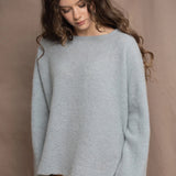 A woman wears a lightweight pointelle cashmere sweater jumper in pale blue turquoise with bronze silk skirt