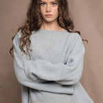 A woman wears a lightweight pointelle cashmere sweater jumper in pale blue turquoise with bronze silk skirt