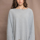 A woman wears a lightweight pointelle cashmere sweater jumper in pale blue turquoise with bronze silk skirt