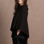 a woman wears a black cashmere cape or poncho over black silk shorts