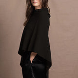 a woman wears a black cashmere cape or poncho over black silk shorts