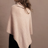 a woman wears a beige coloured cashmere cape or poncho over black silk shorts