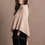 a woman wears a beige coloured cashmere cape or poncho over black silk shorts