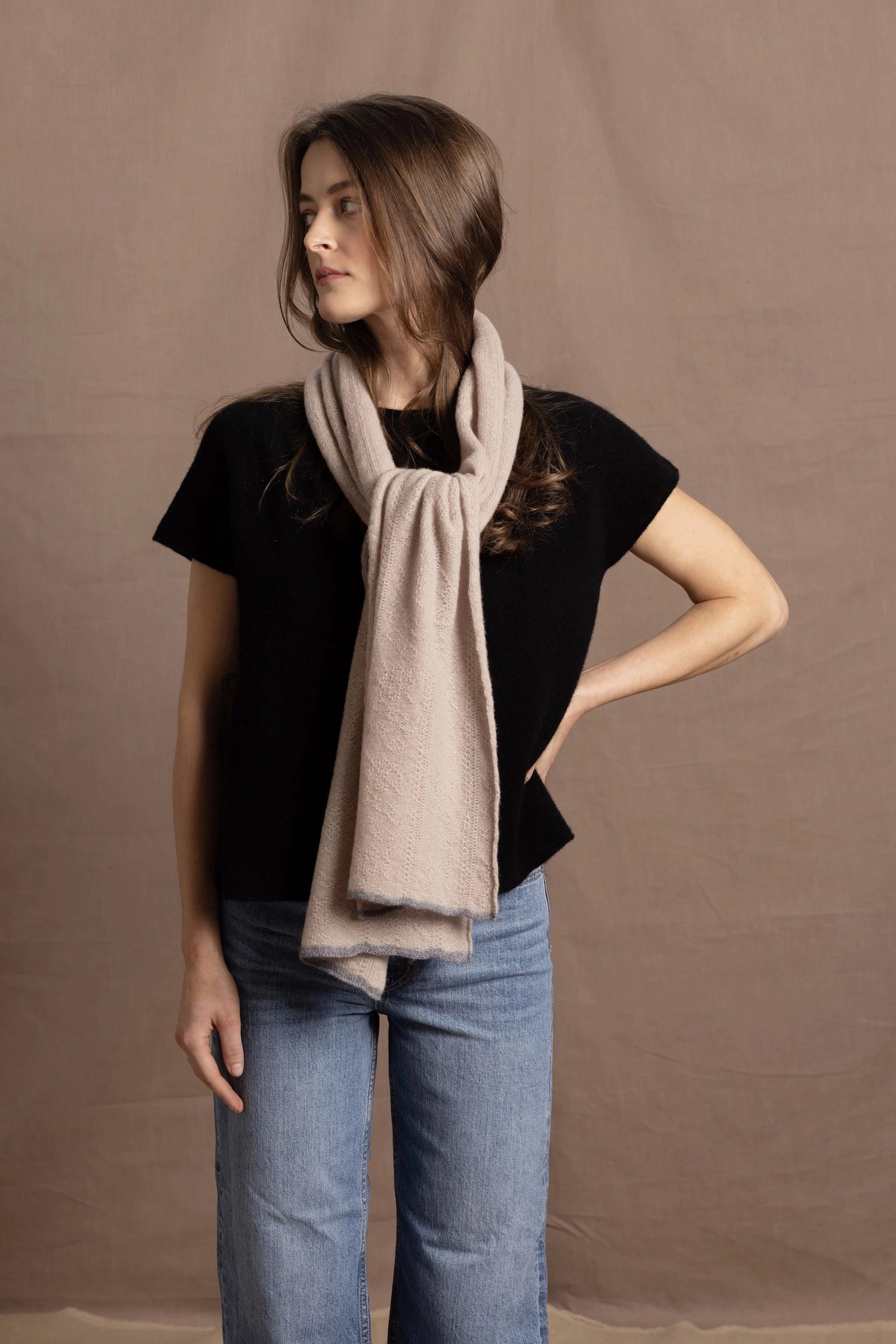 a woman wears a pure 100% cashmere scarf with in beige with a floral pointelle texture over a pure cashmere tshirt in black