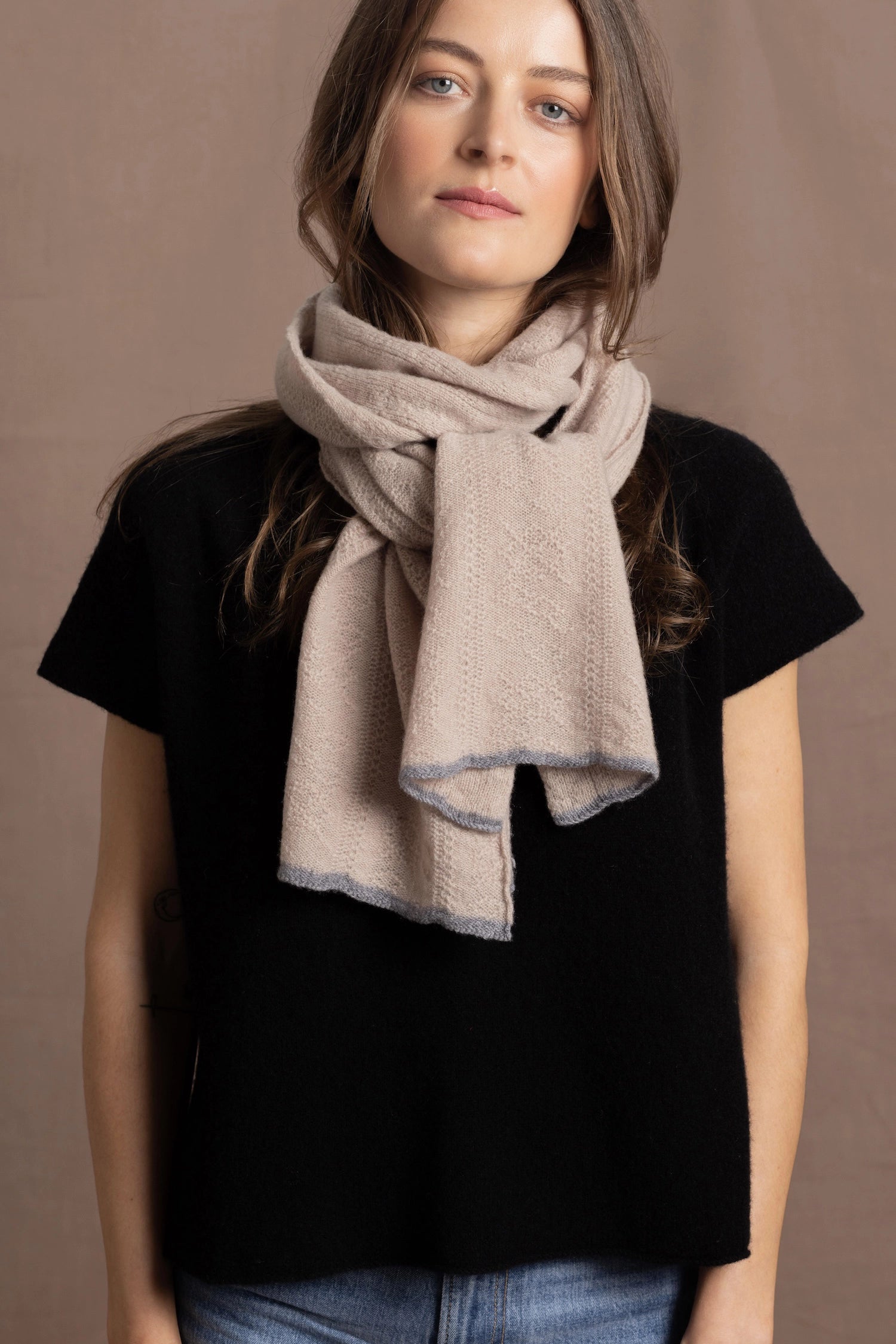 a woman wears a pure 100% cashmere scarf with in beige with a floral pointelle texture over a pure cashmere tshirt in black