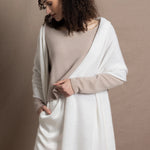 A lady wears a pure cashmere pointelle wrap in white over a beige cropped cashmere sweater and white silk shorts