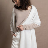 A lady wears a pure cashmere pointelle wrap in white over a beige cropped cashmere sweater and white silk shorts