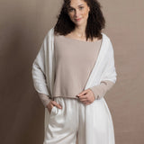 A lady wears a pure cashmere pointelle wrap in white over a beige cropped cashmere sweater and white silk shorts