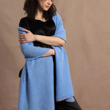 Lady wears a large cashmere wrap shawl in a bright cerulean blue over her shoulders in a full black silk outfit