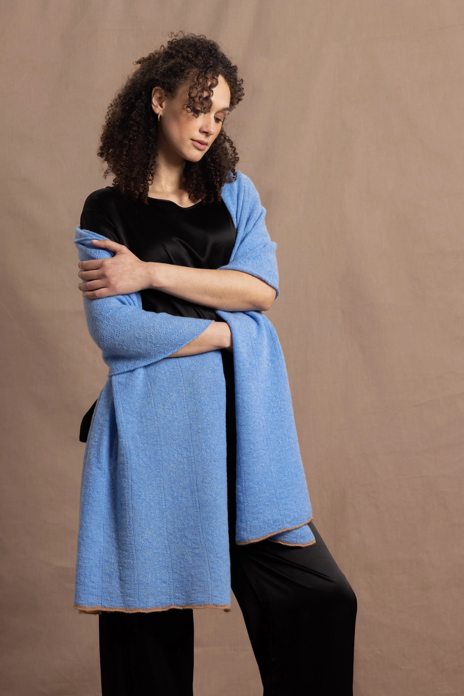 Lady wears a large cashmere wrap shawl in a bright cerulean blue over her shoulders in a full black silk outfit
