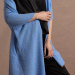 Lady wears a large cashmere wrap shawl in a bright cerulean blue over her shoulders in a full black silk outfit