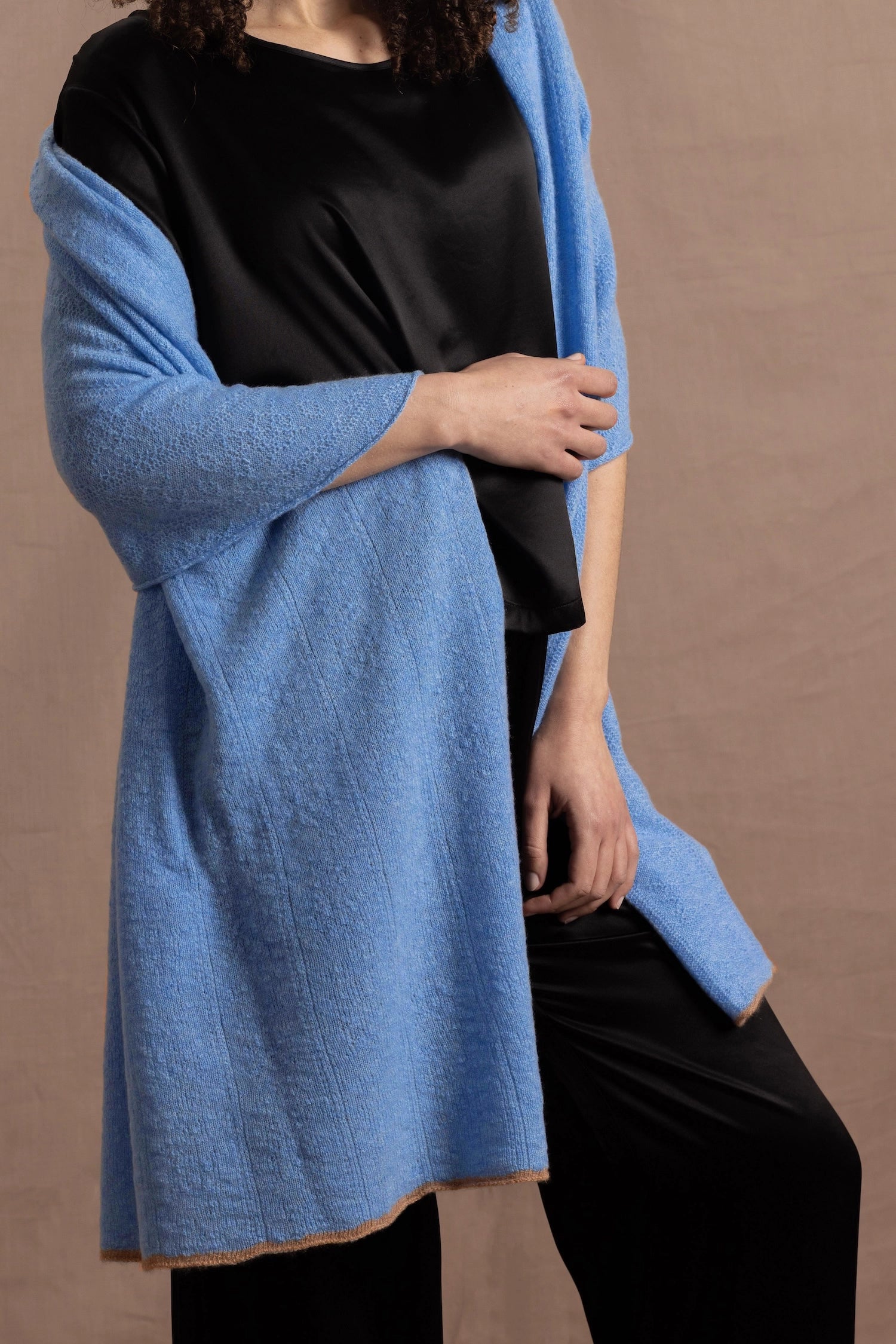 Lady wears a large cashmere wrap shawl in a bright cerulean blue over her shoulders in a full black silk outfit