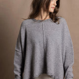 A woman wears a pure cashmere sweater that is oversized in grey 
