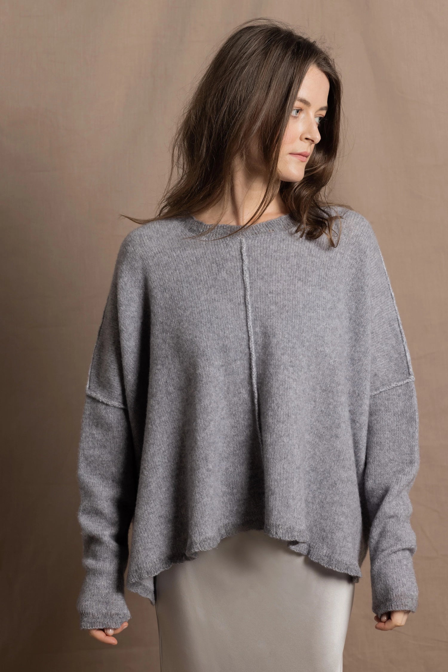 A woman wears a pure cashmere sweater that is oversized in grey 