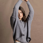 A woman wears a pure cashmere sweater that is oversized in grey with a silver skirt