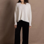 A woman wears an oversized 100% cashmere sweater in Ivory with black silk trousers