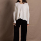 A woman wears an oversized 100% cashmere sweater in Ivory with black silk trousers
