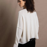 A woman wears an oversized 100% cashmere sweater in Ivory with black silk trousers