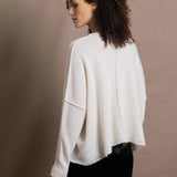 A woman wears an oversized 100% cashmere sweater in Ivory with black silk trousers