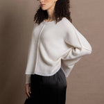 A woman wears an oversized 100% cashmere sweater in Ivory with black silk trousers